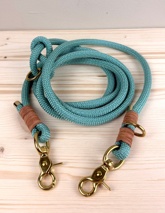 Eine handgefertigte salbeigrüne Hundeleine aus 10mm PPM-Tau mit brauner Ledertakelung und goldenen Messingkarabinern von Lottes Fellfreunde.