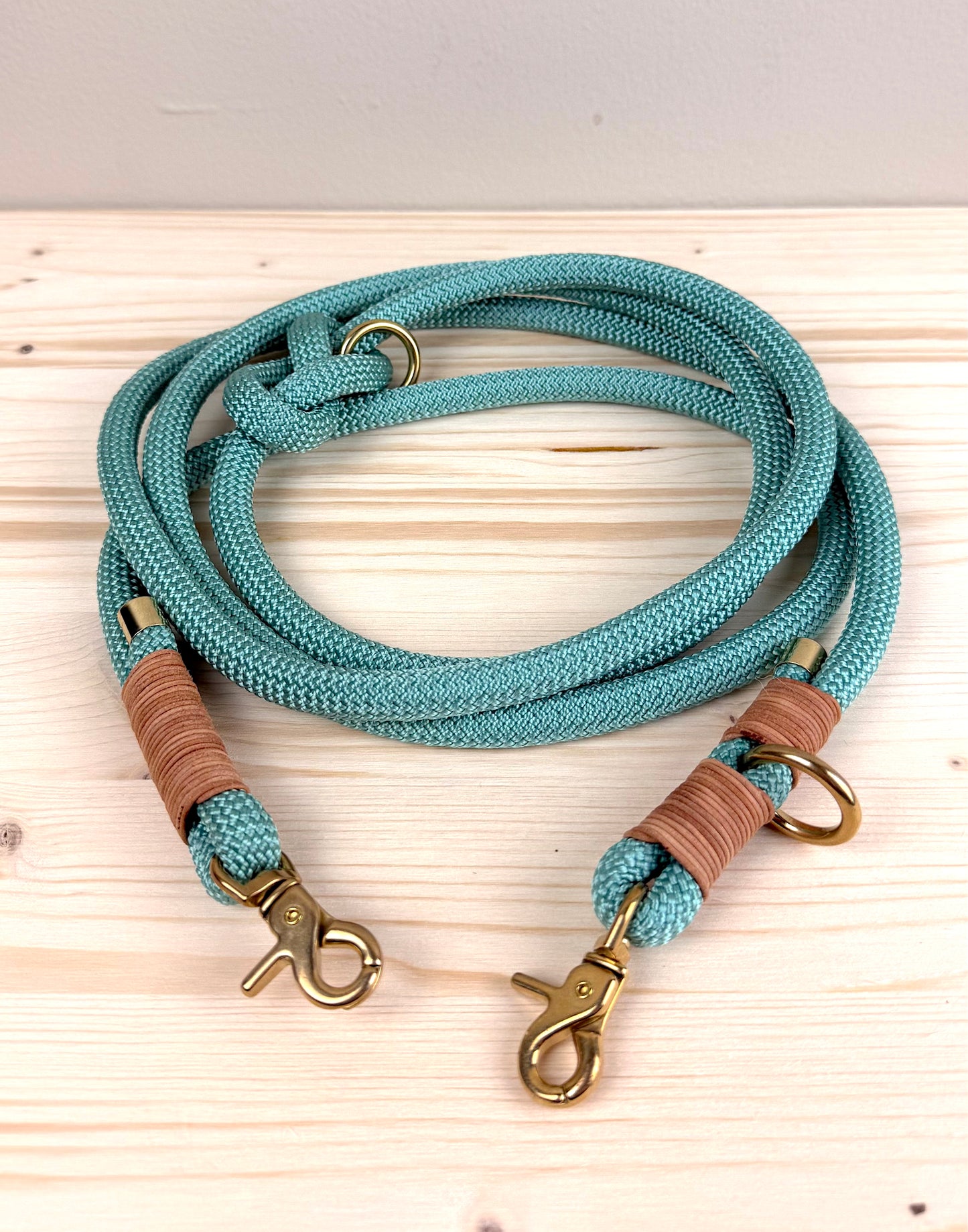 Eine handgefertigte salbeigrüne Hundeleine aus 10mm PPM-Tau mit brauner Ledertakelung und goldenen Messingkarabinern von Lottes Fellfreunde.
