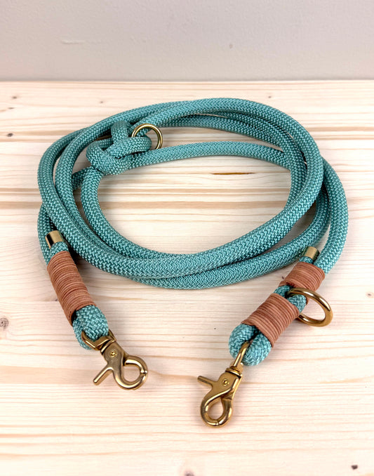 Eine handgefertigte salbeigrüne Hundeleine aus 10mm PPM-Tau mit brauner Ledertakelung und goldenen Messingkarabinern von Lottes Fellfreunde.